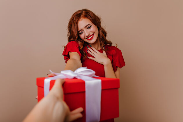 圣诞老人高兴的红发女人在享受圣诞礼物有兴趣的微笑女孩庆祝新年时间礼物室内