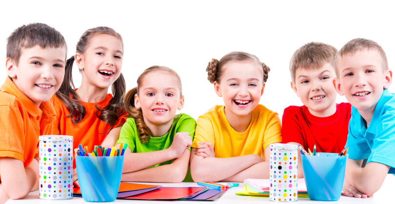 欢呼一群孩子坐在桌子旁 手里拿着记号笔 蜡笔和彩色纸板人童年艺术