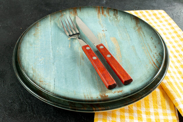 刀叉底视图餐刀和餐叉放在盘子上 黄色和白色格子餐巾放在黑色的地面上盘子炊具容器