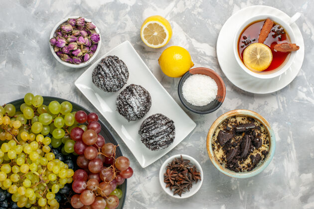 餐俯瞰巧克力蛋糕与柠檬葡萄和茶的白色表面食物菜美食