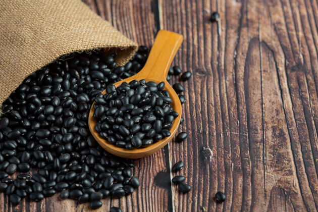 食品黑豆放在小木勺旁边的麻袋里装满了黑豆植物能源草药