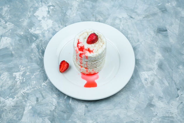 米糕白色的米糕放在一个盘子里 上面有草莓 在浅蓝色的大理石背景上俯视食物甜的蒸汽