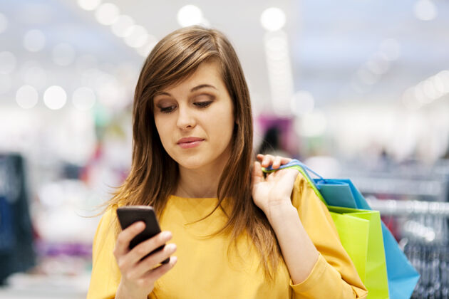 入口在商店里用手机发短信的年轻女子升华下降购物中心