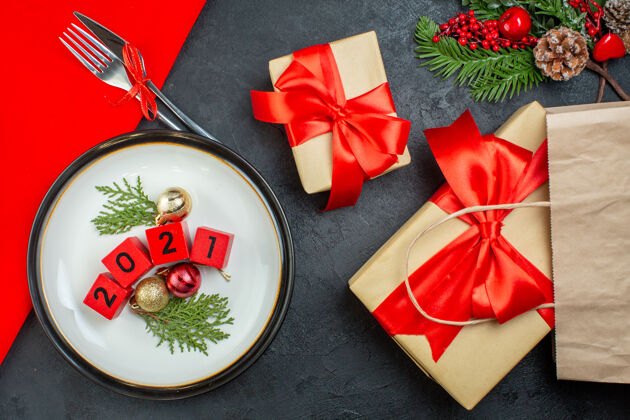 圣诞俯视装饰配件的数字在一个盘子和美丽的礼物冷杉枝针叶树锥在一个黑暗的表树枝冷杉针叶树