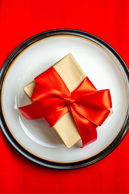 观看国家圣诞大餐背景特写图 黑色背景上的红色餐巾上的空盘子上有蝴蝶结形状的红丝带宝石鞠躬餐巾