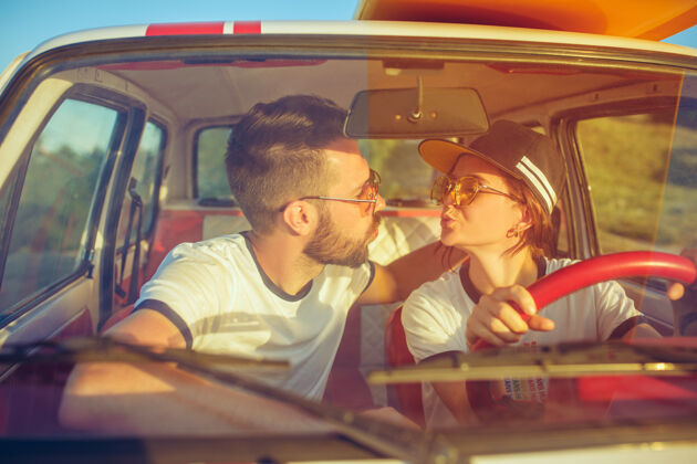 日落一对谈笑风生的浪漫情侣坐在车里 外出旅行篝火年轻情侣