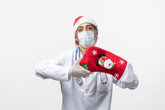 病毒正面图白色墙壁上戴着大节日袜子的男医生可维圣诞病毒肖像圣诞节男医生