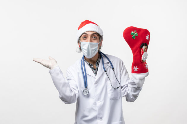 肖像正面图白色地板上戴着大节日袜子的男医生感染了圣诞病毒男人职业制服