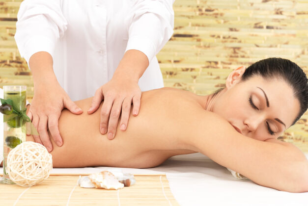 女人在spa沙龙进行背部按摩美容治疗理念手吸引脊柱