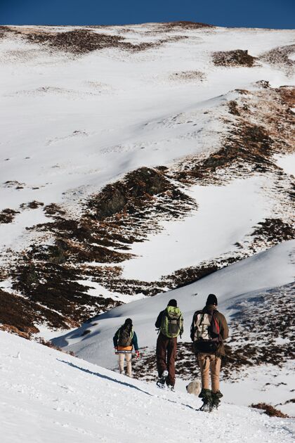 风景垂直高角度拍摄的徒步旅行者与背包在雪山远足高角度雪