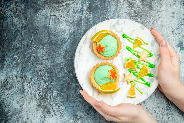 食物俯视图小馅饼与绿色糕点奶油和柠檬片在妇女手中的盘子在黑暗的桌子上自由的地方深色切片容器