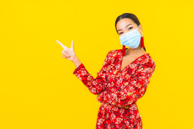 疾病肖像美丽的亚洲年轻女子戴上防冠状病毒或冠状病毒的面具在黄色的墙上护理肖像医疗保健