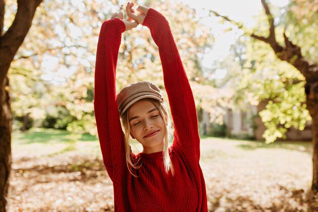 秋天美丽的金发女孩在秋天的公园里感到快乐可爱的穿着红毛衣的女人在树叶间摆姿势花森林叶子