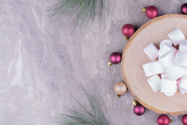 健康白色的棉花糖放在木制的盘子里 周围是红色的圣诞球糕点咖啡馆小吃