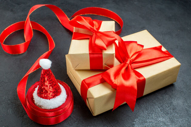 圣诞老人侧视图美丽的礼物与红丝带和圣诞老人帽子在一个黑暗的桌子上风景惊喜帽子