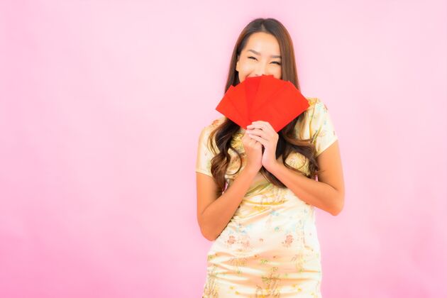 女孩在粉红色的墙上画一幅美丽的亚洲年轻女子拿着红包人钱节日
