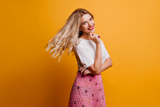 青少年俏皮的金发女孩表达幸福优雅时尚的女士在橙色的墙上冷享受表情优雅