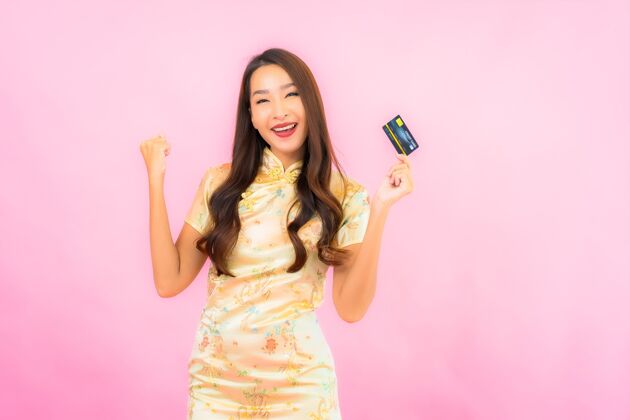 金融在粉红色的墙上画一幅美丽的亚洲年轻女子的画像 上面有信用卡和手机付款日本人人