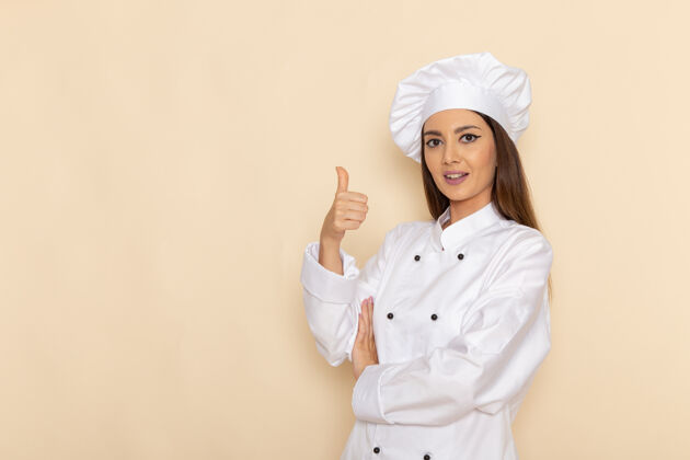 职业身着白色厨师服的年轻女厨师在浅白的墙上摆姿势微笑的正面图服装微笑年轻人