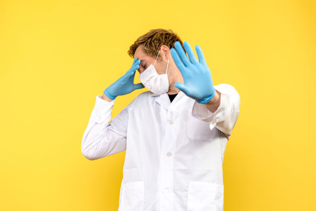 医学前视图黄色背景上的男医生健康大流行科维德医生肖像冠状病毒外套