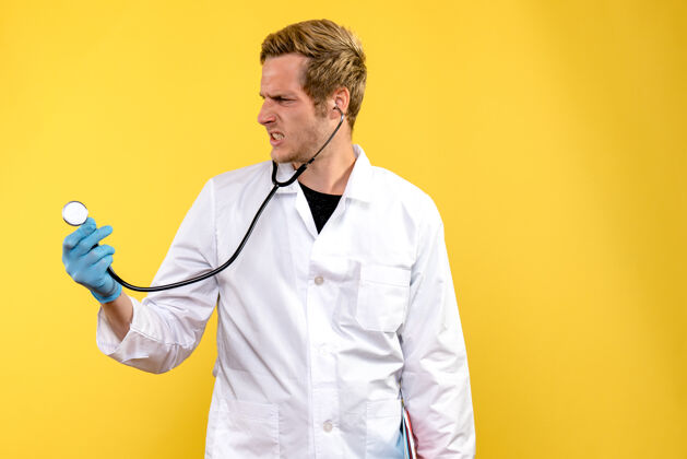 人前视图男性医生用听诊器对黄色背景的医疗保健病毒医疗器械男性护士