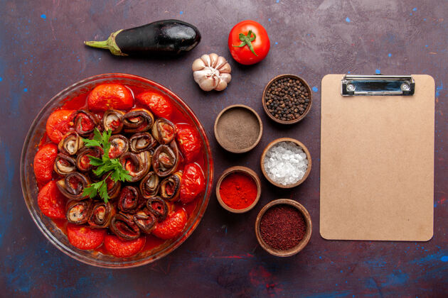 盘子顶视图熟蔬菜餐番茄和茄子与调味品在黑暗的桌子上生的菜肴食物