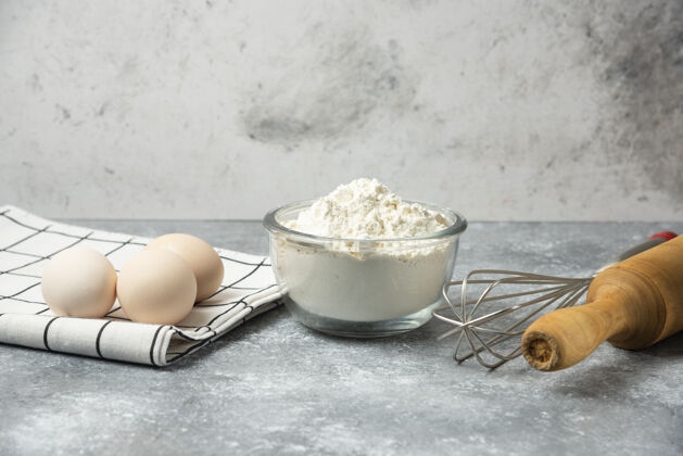 做的一碗面粉 鸡蛋和厨房工具放在大理石桌上生的别针奶制品