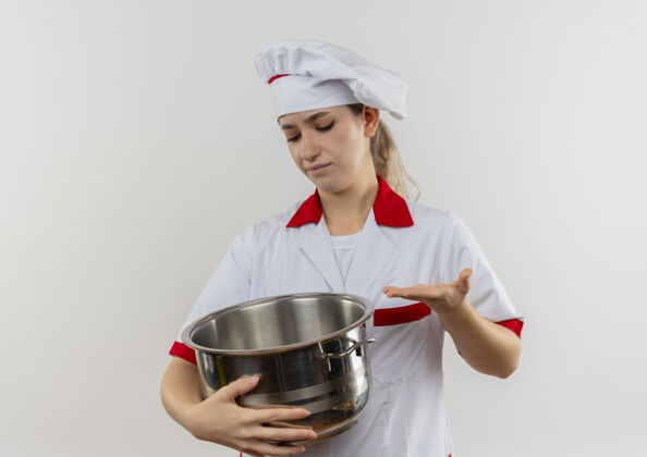 不放年轻漂亮的厨师穿着厨师制服 拿着锅 看着锅 用手指着它 把它隔离在空白处指着拿着制服