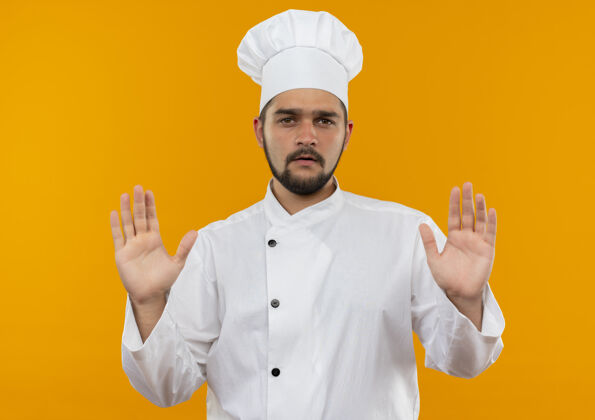 手穿着厨师制服的年轻男厨师 手空空的 孤立在橙色的空间里男性厨师烹饪