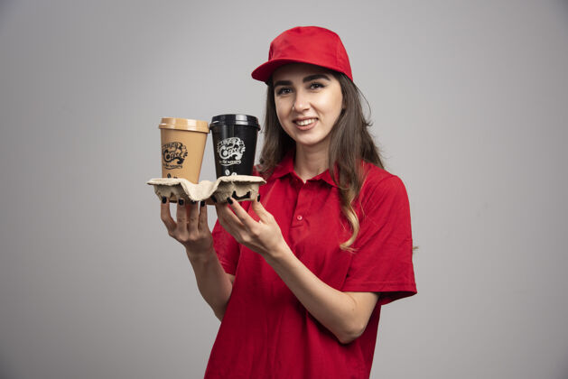 饮料穿着红色制服拿着咖啡杯的漂亮女送货员承运人送货职业