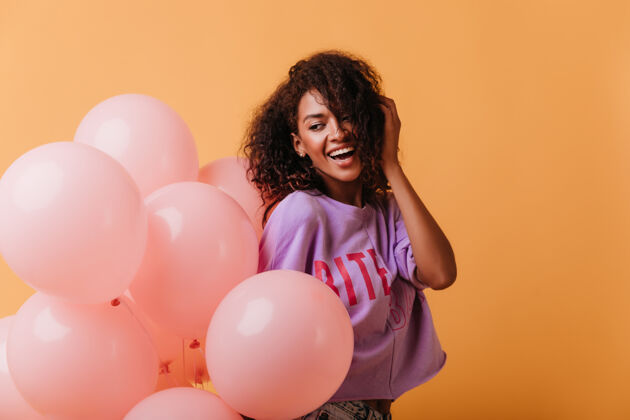 黑色无忧无虑的年轻女士手持氦气球在橙色和微笑笑积极的黑人女孩庆祝生日年轻肖像表情