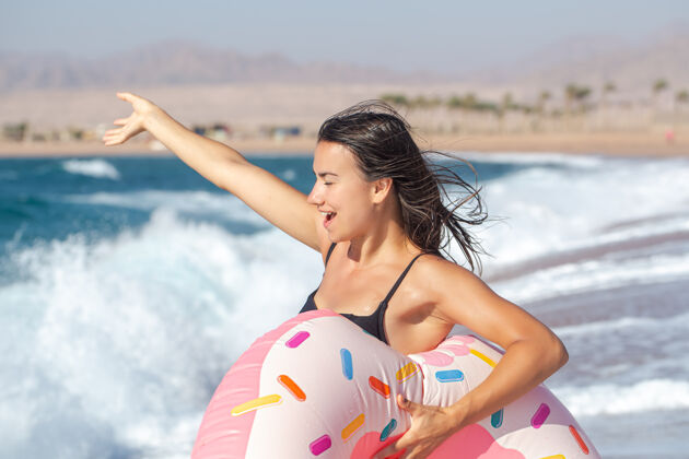 休息一个快乐的年轻女子 在海边有一个甜甜圈形状的游泳圈度假休闲娱乐的概念女人假期假日
