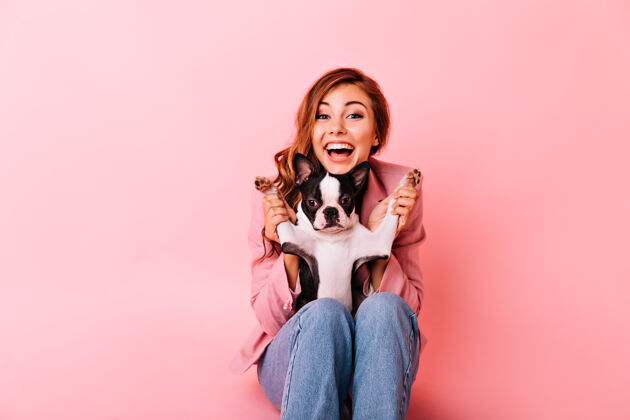 斗牛犬穿着牛仔裤的快乐女孩和有趣的小狗玩耍室内照片是一位兴奋的姜黄色女士 留着卷发 和她的小狗在一起主人积极有趣