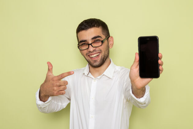 衬衫身穿白衬衫的男上班族正拿着手机微笑着站在绿色的墙上劈刀电话微笑