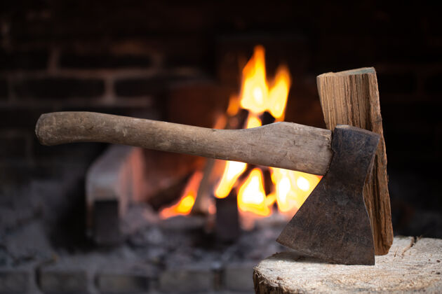 火一把斧头插在燃烧着的壁炉旁的木桩上村庄里舒适和放松的概念乡村篝火斧头