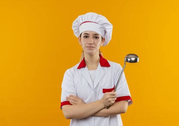 年轻年轻漂亮的厨师身着厨师制服 站在橙色的空间里 抱着勺子 姿势封闭复制空间姿势