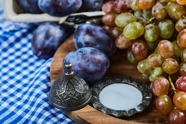农业新鲜的李子和一串葡萄放在木盘上有机葡萄多汁