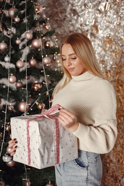 庆祝房间里的女人穿白色毛衣的女孩圣诞树旁的女士模特欢呼圣诞节