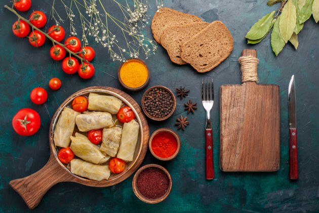桌子俯瞰图美味的肉食卷心菜内卷面包和新鲜西红柿在深蓝色的桌子上西红柿里面肉