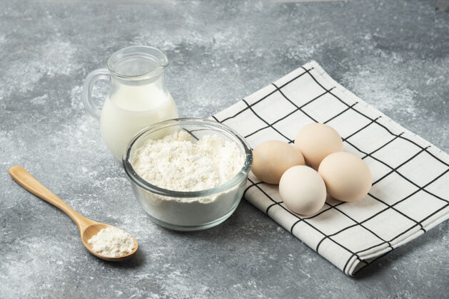 奶制品一碗面粉 鸡蛋和牛奶放在大理石上勺子厨房桌布