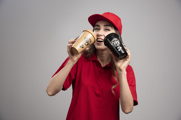 女人穿着红制服的女送货员在喝咖啡事业员工女孩