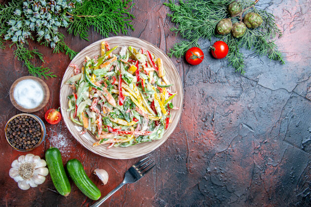 蔬菜沙拉顶视图蔬菜沙拉在盘子叉子上西红柿松枝黄瓜大蒜在暗红色桌子上自由的地方午餐食物大蒜