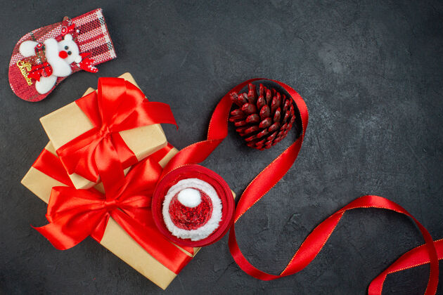 扣件俯瞰美丽的礼物与红丝带和圣诞老人帽针叶树锥圣诞袜在黑暗的桌子上头顶夹子头发幻灯片