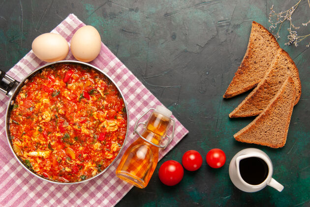 午餐顶视图深绿色背景上的炒鸡蛋 西红柿和面包香料黑胡椒早餐