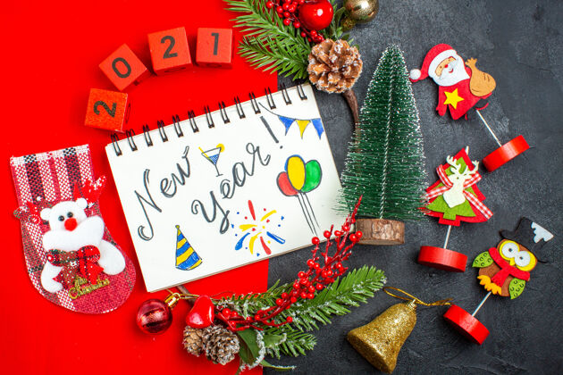 螺旋笔记本上图为螺旋形笔记本 带有新年书写和绘图装饰配件杉木树枝红色餐巾上的xsmas袜子编号和深色背景上的圣诞树餐巾圣诞书写
