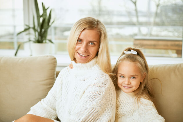 妈妈家庭 人际关系 世代 爱情和亲密的概念年轻时尚的欧洲妈妈 留着一头直发 坐在舒适的沙发上 坐在她可爱的女儿旁边 微笑着放松沙发小肖像