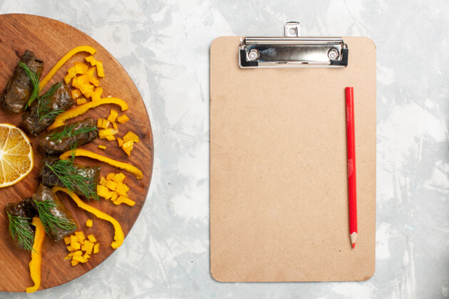 肉俯视图切碎的甜椒和叶子 在白色的桌子上放一个记事本美味甜椒叶子