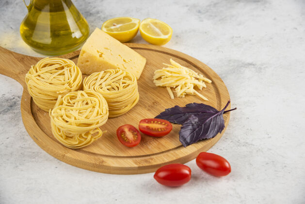 油在木板上放意大利面 蔬菜和奶酪罗勒柠檬西红柿