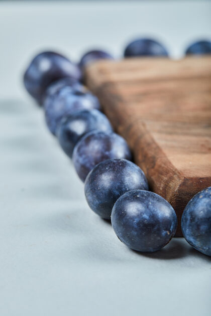 李子一群新鲜的李子围在木板上蓝色成熟紫罗兰