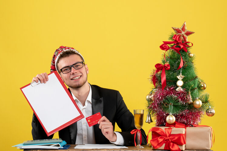 男性工人正面图：手持银行卡的男工围着圣诞树 黄色的礼物专业人士颜色小